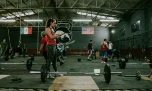 Ludzie trenujący crossfit w siłowni z flagami Meksyku i USA w tle.