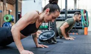 Kobieta i mężczyzna wykonują pompki na siłowni CrossFit.