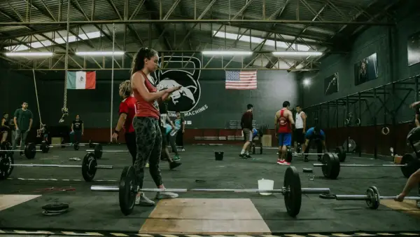 Ludzie trenujący crossfit w siłowni z flagami Meksyku i USA w tle.